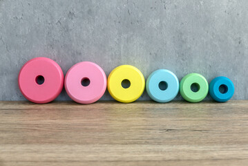 Colorful Wooden Discs of kids toy Arranged by Size on Wooden Surface