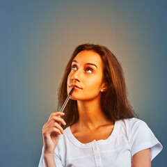 Obraz premium Pensive young woman planning future projects, holding pen and lo