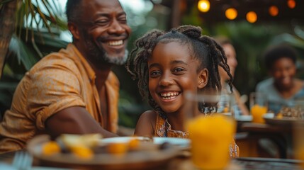 A happy African American father and daughter enjoying a meal together outdoors.
