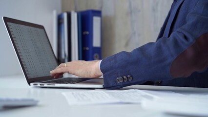Businessman with blue suit is working on his laptop, typing on the keyboard in the office. Business concept