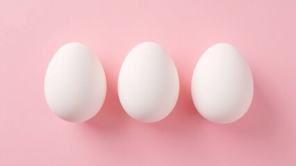Three white eggs arranged on a soft pink background, showcasing minimalist design and simplicity for food or decor themes