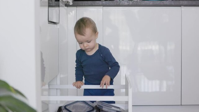 Toddler playing with tupperware in kitchen