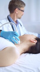 Obraz premium Doctor man wearing blue protective gloves is using ultrasound equipment on the neck of a patient woman, lying for examination. Medicine concept
