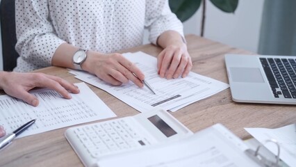 Professional female bookkeeper with a colleague are working on business finances. using calculator and laptop. Finance audit and taxes