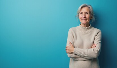 Senior woman with confident smile posing against turquoise background with copy space