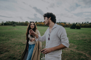 A couple enjoying a relaxed outdoor gathering, sharing a moment with wine in hand. The scene...
