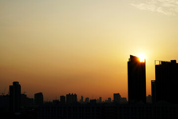 Fototapeta premium The sunset with clouds in the sky behind high building towers over the city.