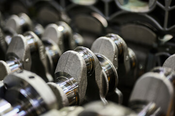 The crankshaft of an automobile engine, many products lie in a row. Warehouse of spare parts of an...