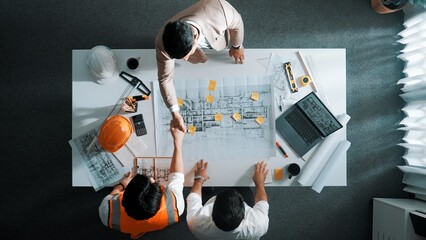 Top down aerial view of architect engineer team shake hands and discussing about building...
