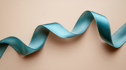 A blue ribbon is curled up on a tan background. The ribbon is long and has a smooth texture. Concept of elegance and sophistication, as the ribbon's color