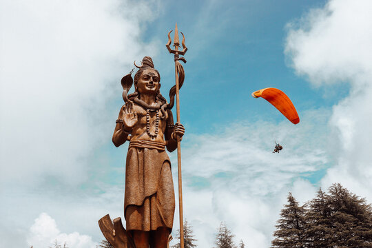 Person paragliding near Statue of Hindu God Shiva