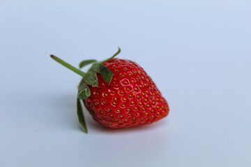 One red strawberry with green stem, isolated on white background