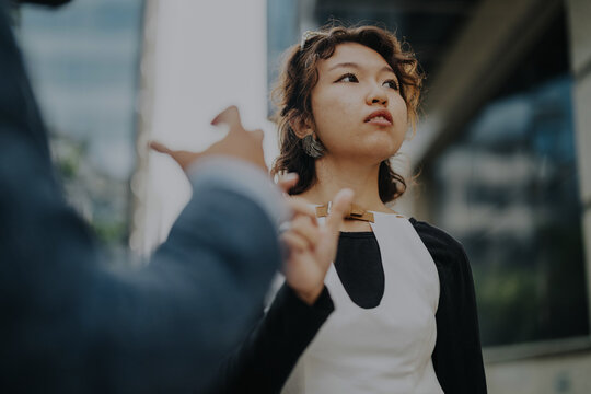 A confident businesswoman engaged in a discussion outside in an urban city setting. The image captures communication, professionalism, and a modern corporate atmosphere.