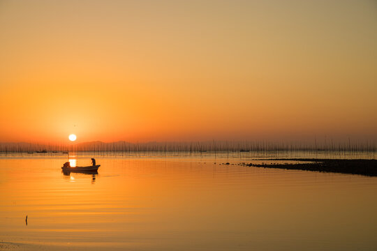 Person on a boat in a body of water at sunset