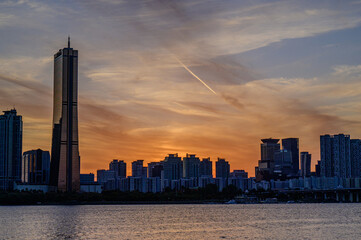 Obraz premium Sunset and silhouette view of 63 Building and high rise buildings of financial district with Wonhyo Bridge on Han River at Yeouido near Yeongdeungpo-gu, Seoul, South Korea