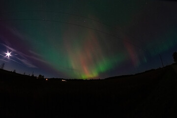 Aurora and the full moon dazzling the night sky