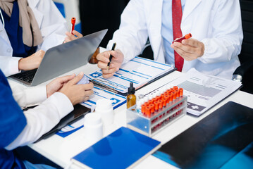 Medical team having a meeting with doctors in white lab coats and surgical scrubs seated at a table discussing a patients working