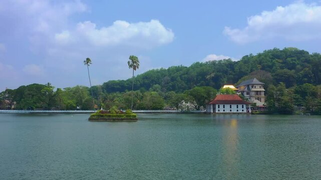 Aerial footage of Sri Dalada Maligawa, the Sacred Tooth Relic Temple, by the peaceful Kandy Lake in Sri Lanka. Showcasing cultural heritage amid lush scenery, perfect for travel and tourism media.