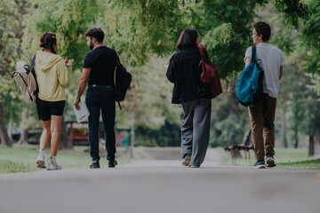 Obraz premium A group of students and a professor enjoy a casual walk through a park, taking a break after classes. They are seen in a relaxed environment, promoting educational and social interaction.