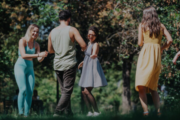 Fototapeta premium A joyful group of diverse friends having fun in a lush park, basking in the sunshine and sharing laughter while enjoying outdoor activities.