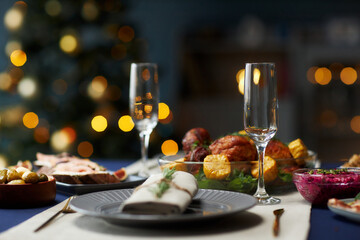 Still life shot of empty champagne glass served on dining table with festive turkey dinner and colorful christmas lights in blurred background, copy space