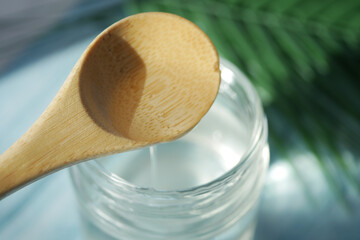 coconut oil pouring from a spoon into a container 