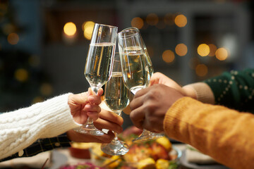 Hands of people raising toast clinking glasses with champagne celebrating Christmas together at...