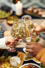 Vertical shot of hands of people raising toast clinking glasses with champagne celebrating Christmas together at home party, copy space