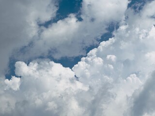 Obraz premium The blue sky is covered by thick white clouds during the day. The sky and clouds in summer are very bright, soft and fluffy.