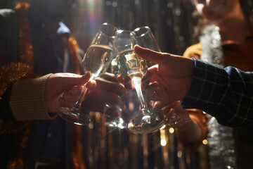 Cropped shot of people clinking glasses of champagne standing in top light while celebrating...