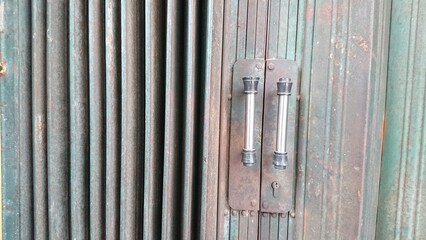 Closed and Locked Weathered Green Metal Rolling Door with Industrial Themes Chrome Handles
