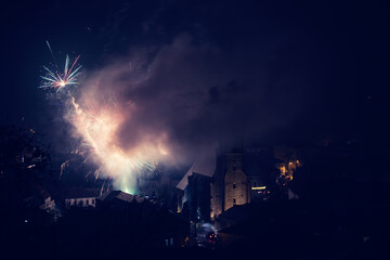 Gold Fireworks Light Up The Night Sky Over A Picturesque Rural Fairground With White Barns And Small Churches, Creating A Festive And Vibrant Atmosphere Against The Dark Backdrop.