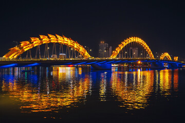 Dragon Bridge over the Han River is a famous landmark in the city of Da Nang in Vietnam at night with a golden backlight