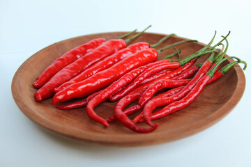 Some fresh big red chillies, on wooden plate, on white background