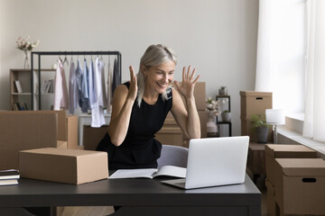 Amazed mature woman ecommerce owner sales manager look on laptop screen excited with great work...