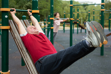  Elderly man doing exercises on a horizontal bar at an outdoor sports ground