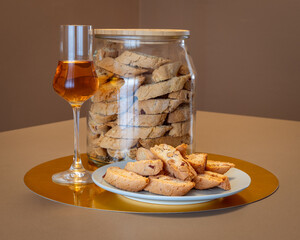 Glass of Vin Santo and almond cantucci biscuits on golden surface perfect for a classic Italian...