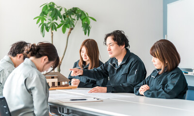 ミーティング・会議・商談で厳しく指導する作業着姿の男性ビジネスマン
