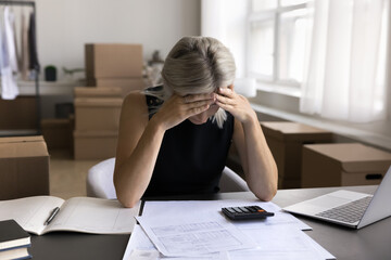 Upset mature businesswoman entrepreneur do accounting paperwork think about tax bill debt lack...