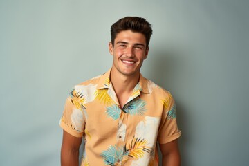 A man in a yellow shirt with palm trees on it is smiling