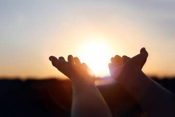 New Year's sunrise, brilliant light and rays of light shining through hands stretched out toward the rising sun, concept of hope and wishes for the future
