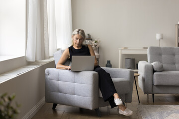 Busy senior woman involved in part time job on pension blogging copywriting study material for...