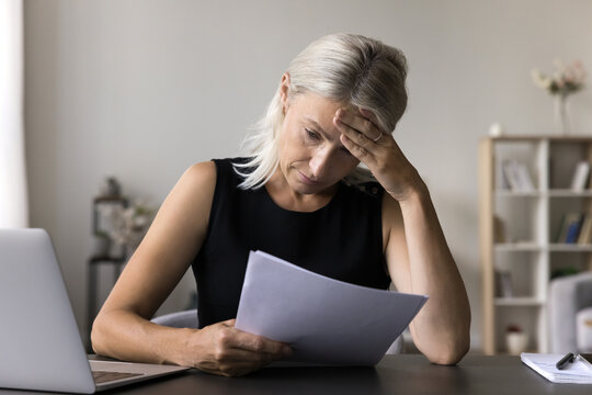 Confused upset older woman self employed entrepreneur think about financial debt possibility of business bankruptcy losing money. Concerned senior female freelancer receive bad news in official paper
