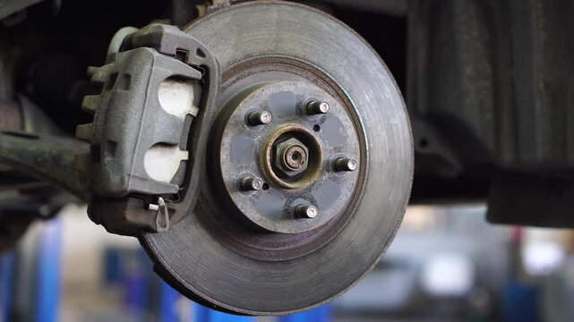 Auto mechanic replaces brake disc on car at repair shop. Auto repair shop.