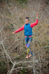 A tightrope walker walks along a cable stretched over a canyon.