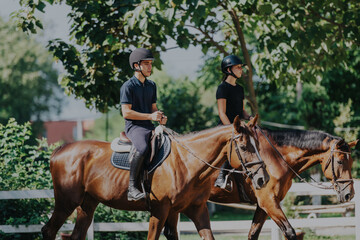 Fototapeta premium Two equestrians enjoy riding their horses through a scenic countryside setting. The image captures a sense of tranquility and outdoor activity, perfect for leisure, fitness, and connection with nature