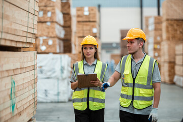 Team engineer carpenter wearing safety uniform and hard hat working holding clipboard checking quality of wooden products at workshop manufacturing. man and woman worker wood warehouse industry.