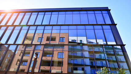 Exterior of modern building with many windows against blue sky, low angle view.