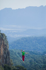 A tightrope walker walks along a cable stretched over a canyon.