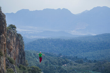 A tightrope walker walks along a cable stretched over a canyon.